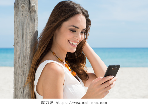 一位美女在海滩上看手机微笑女孩读短信
